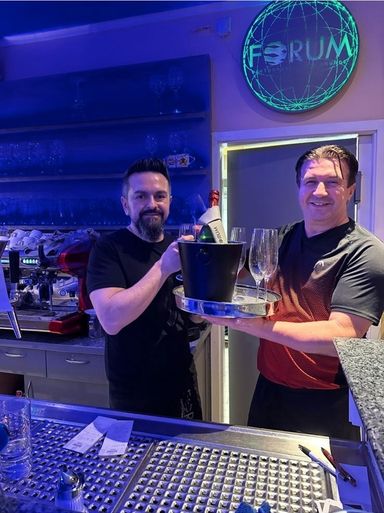Jani und Ivo Budulica an der Bar im Restaurant FORUM Nagold Flasche Sekt anrichten